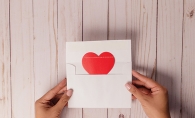 A red heart coming out of a white envelope