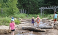 Children walk in the water at Tamarack Nature Center.