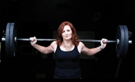 A woman holds a barbell in a photo shoot for BearFitness about empowering women.