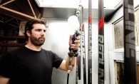  Charlie Igo applies a layer of clear coat to a fresh batch of lacrosse sticks.