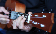 A man strums a ukulele.