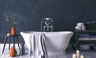 A soaker tub sits in a newly-remodeled bathroom surrounded by candles, towels and other bathroom items.