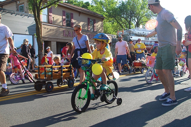 A kid rides a bike in the parade at White Bear Lake Marketfest 2019.
