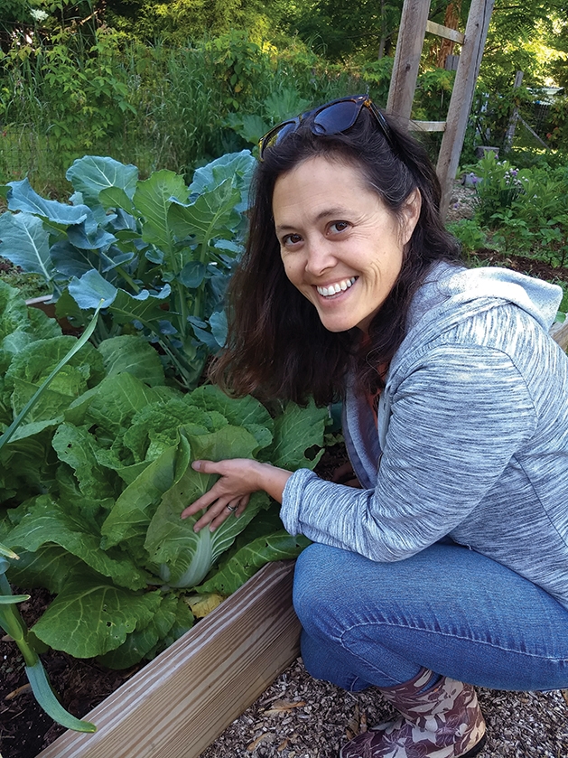 Michelle Bruhn in her garden next to leafy greens