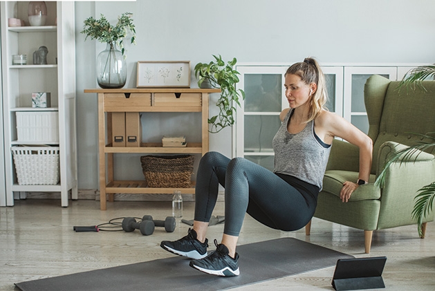 A woman performs online exercises from the YMCA at home.