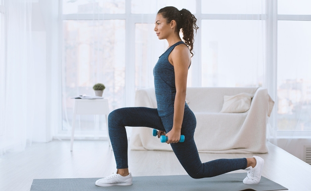 Athletic woman doing lunges with weights.