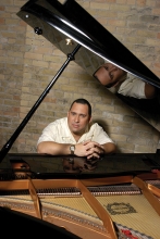 Pianist Nachito Herrera sits at a piano