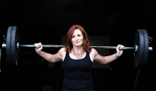 A woman holds a barbell in a photo shoot for BearFitness about empowering women.