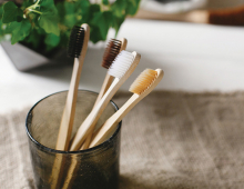 Four bamboo toothbrushes sit in a toothbrush holder.