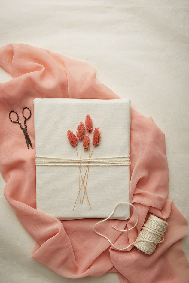 A gift wrapped with twine and pink plants.